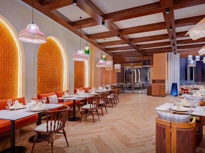 Moderne hotel lounge met houten balkenplafond, oranje banken en tafels.