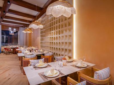 Gezellig restaurant met houten tafels, comfortabele stoelen en warme verlichting.