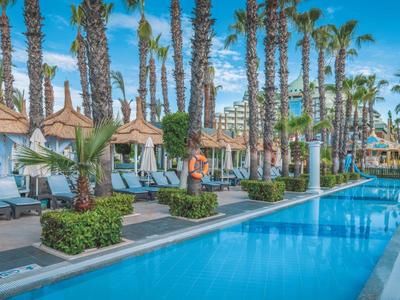 Piscina lunga circondata da palme e lettini in una giornata soleggiata