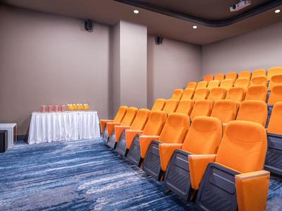 Kleine vergaderruimte met oranje stoelen en blauw tapijt.