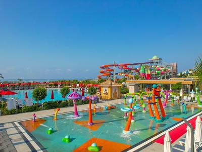 Kleurrijk waterpark met glijbanen en waterspelletjes onder blauwe lucht.