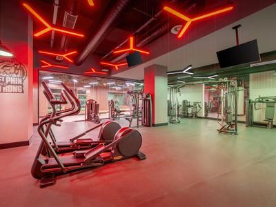 Palestra moderna con attrezzi per allenamento e illuminazione al neon rossa sul soffitto.