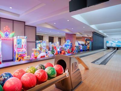 Moderne bowlingbaan met kleurrijke bowlingballen en levendige automaten op de achtergrond.