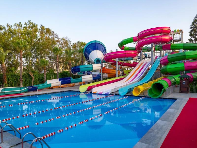 Kleurrijke glijbanen naast een groot zwembad in een hotelresort.