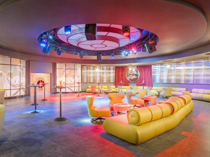 Grote moderne hotel lounge met kleurrijke zitplaatsen en verlicht plafondaccent.