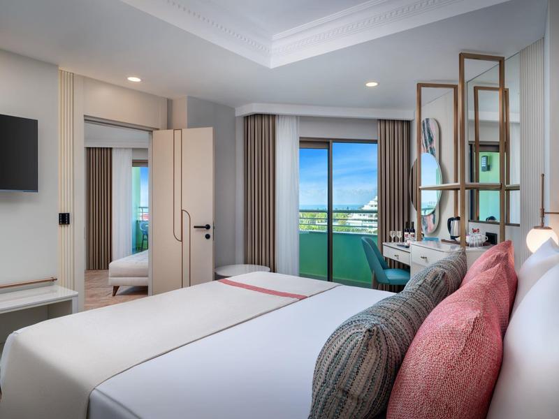 Moderne hotelkamer met twee bedden, balkon en uitzicht op zee.