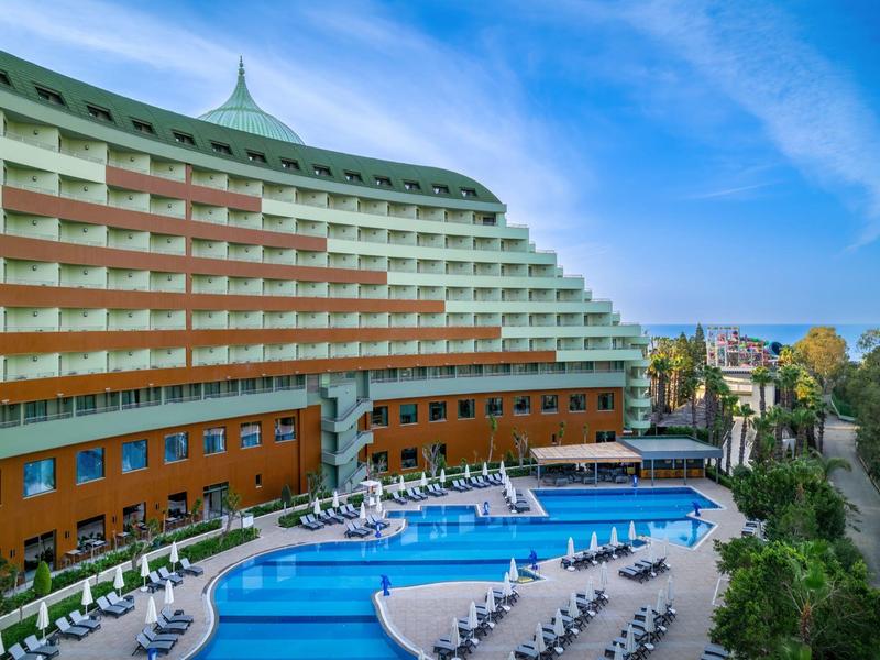 Modern hotel met groot zwembad en ligstoelen onder een blauwe lucht