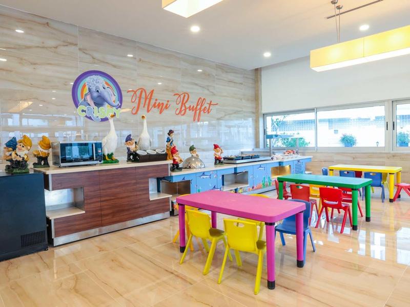 Sala de desayuno luminosa y moderna con mesas y sillas de colores en un hotel.