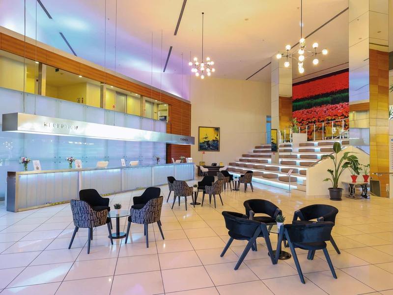 Restaurante moderno de hotel con sillas negras, mesas blancas y escaleras al área superior.