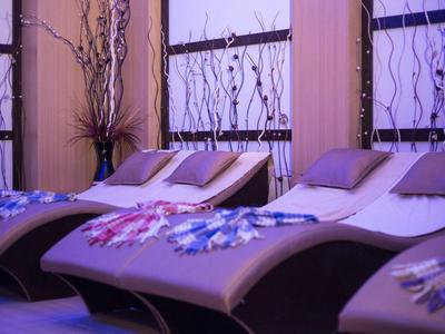 Drei braune Liegen mit bunten Decken und Kissen vor dekorativen Fenstern in entspannter Atmosphäre.