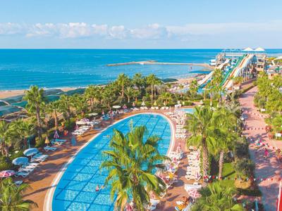 Vista di una piscina dell'hotel con lettini e mare sullo sfondo sotto un cielo azzurro.