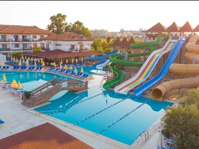 Grande piscina dell'hotel con scivoli d'acqua e lettini al tramonto.