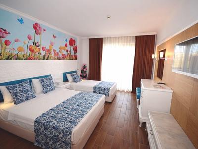 Hotelzimmer mit zwei Betten, blau gemusterten Decken, Holzfußboden und großer Blumenwanddekoration.