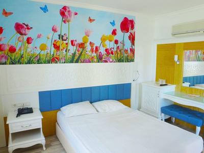 Helles Schlafzimmer mit Doppelbett, blauer Polsterung, Blumenbild an Wand und weißem Schminktisch.