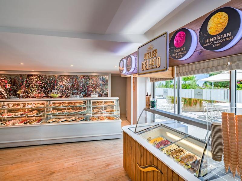 Modernes Eisdiele-Interieur mit Glasvitrinen, bunten Eissorten und Sonneneinstrahlung durch Fenster.