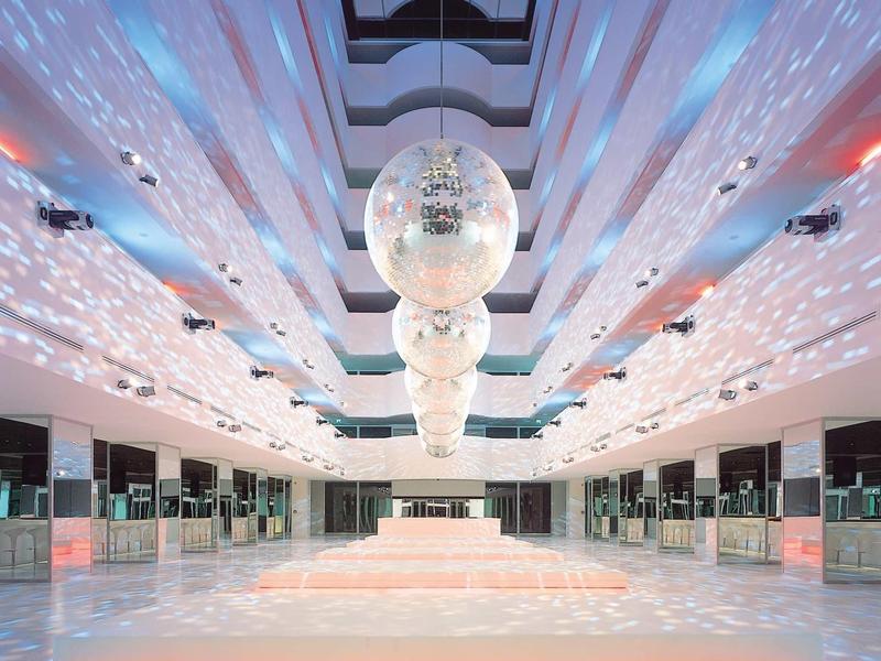 Großer heller Raum mit glänzenden Kugeln und reflektierendem Licht an Decke und Wänden.
