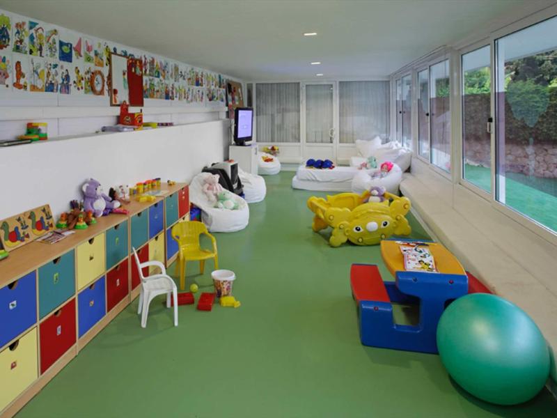 Bunter Kinder-Spielraum mit Sitzsäcken, Spielzeug, bunten Regalen und großen Fenstern zur Gartenseite.