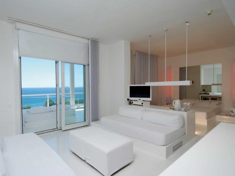 Helles modernes Wohnzimmer mit weißer Einrichtung und großen Fenstern mit Meerblick.