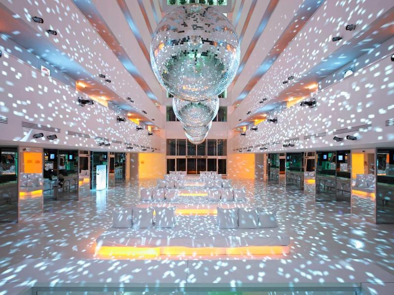 Großer Raum mit spiegelnden Kugeln an der Decke, leuchtendes Licht und funkelnde Reflexionen überall.
