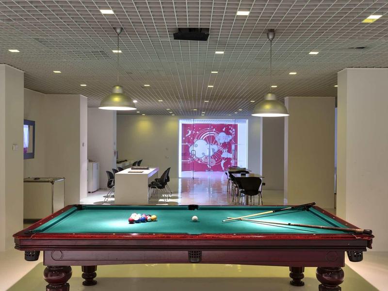 Innenraum mit grünem Billardtisch, braunem Holzgestell und moderner Beleuchtung an der Decke.