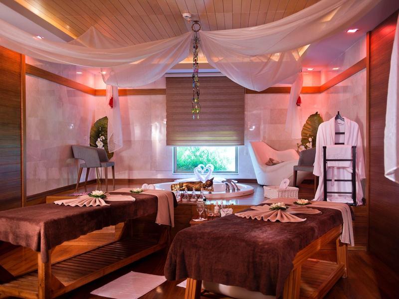 Gemütlicher Wellnessraum mit Massageliegen, sanfter Beleuchtung und weißen Stoffvorhängen an der Decke.