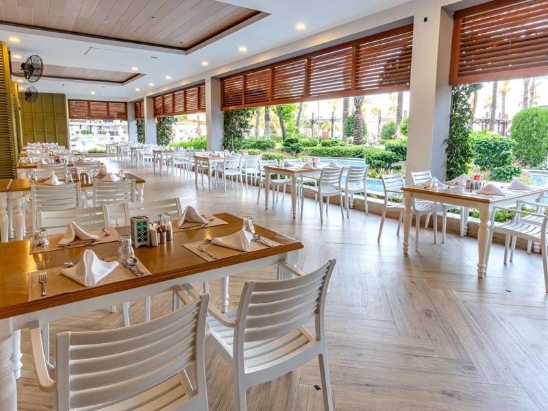 Modernes, helles Restaurant mit Holzböden, weißen Stühlen und großen Fenstern zum Garten.