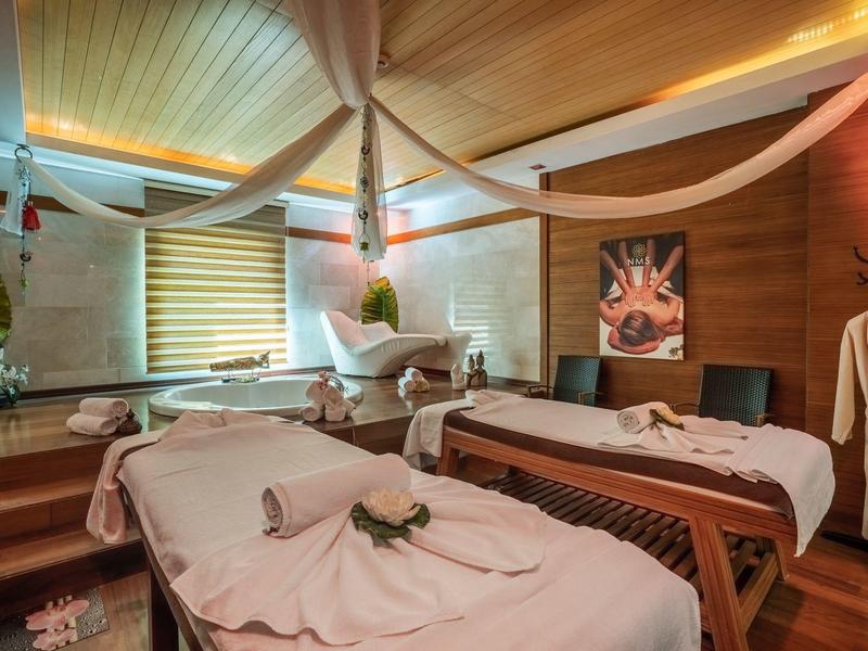 Gemütlicher Wellnessraum mit Holzmöbeln, zwei Massageliegen und sanfter Beleuchtung.