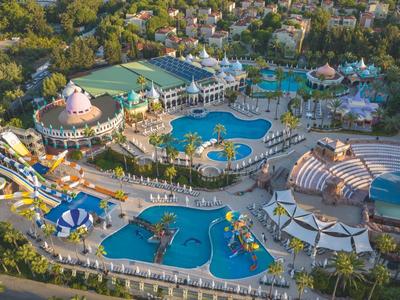 Widok z lotu ptaka dużego parku wodnego z wieloma basenami, zjeżdżalniami i zielenią.