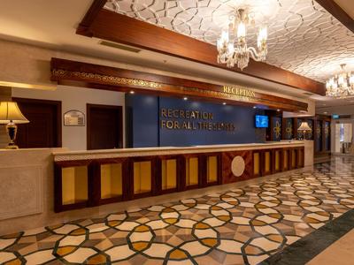 Recepcja hotelu z długim kontuarem i dekoracyjnym wzorem podłogi