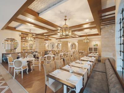 Elegancka restauracja z drewnianym sufitem z belkami i stylowymi, jasnymi meblami.