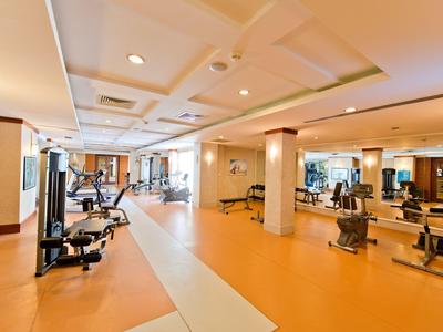 Palestra moderna e luminosa con varie attrezzature e pavimento arancione.