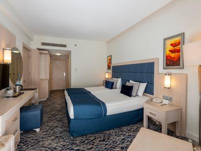 Nowoczesny pokój hotelowy z dużym łóżkiem, niebieskimi akcentami i miejscem do pracy.