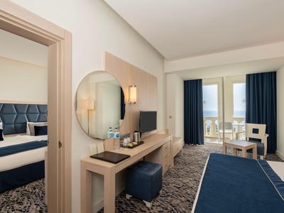 Nowoczesny pokój hotelowy z biurkiem, niebieskim dywanem i balkonem z stołem i krzesłami.