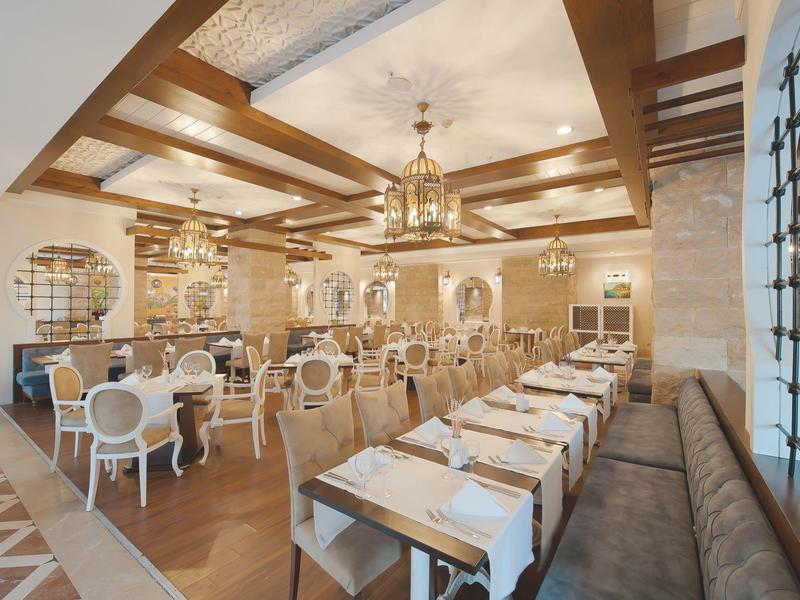 Elegancka restauracja z drewnianym sufitem z belkami i stylowymi, jasnymi meblami.