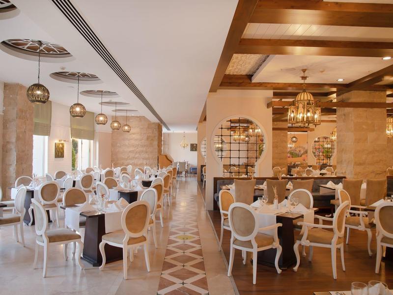 Elegancka restauracja z wygodnymi białymi krzesłami i ciepłym drewnianym wystrojem.