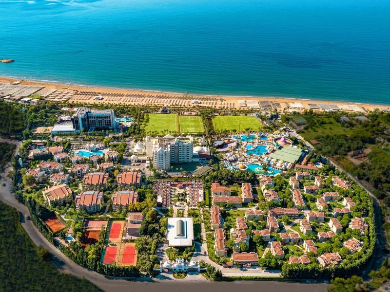 Widok z lotu ptaka na duży ośrodek nadmorski z wieloma budynkami, basenami i bezpośrednim dostępem do morza.