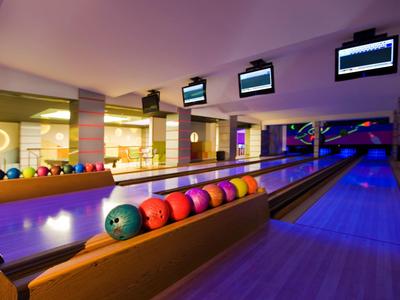 Allée de bowling avec des boules colorées et des écrans dans une salle moderne.