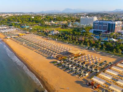 Larga playa de arena con sombrillas y hoteles al fondo en la costa.