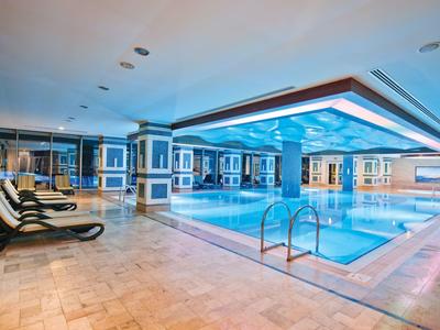 Piscina interior elegante con ventana de techo iluminada y tumbonas en un hotel de lujo.