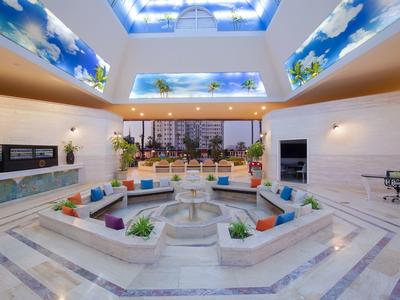 Patio interior con fuente, cojines, plantas y vista a edificios urbanos a la luz del día.