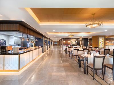 Amplia zona de restaurante moderna con mesas puestas y cocina abierta.