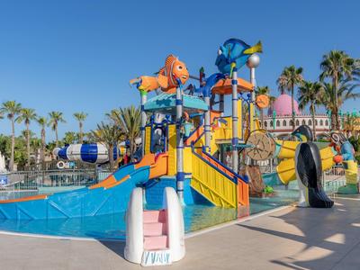 Kolorowy plac zabaw wodny ze zjeżdżalniami i armatkami wodnymi w ośrodku hotelowym przy słonecznej pogodzie.