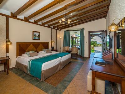 Przytulny pokój hotelowy z dwoma łóżkami, drewnianym sufitem i dostępem do tarasu.