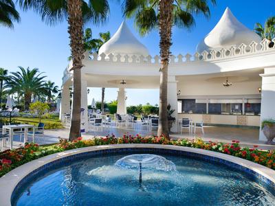 Area esterna elegante con fontana, palme e zona pranzo coperta in un contesto alberghiero