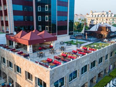 Taras na dachu z stołami i czerwonymi parasolami przy nowoczesnym budynku hotelu