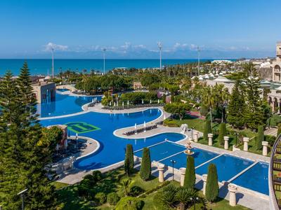 Luxury hotel with expansive pool area and sea view under clear sky.