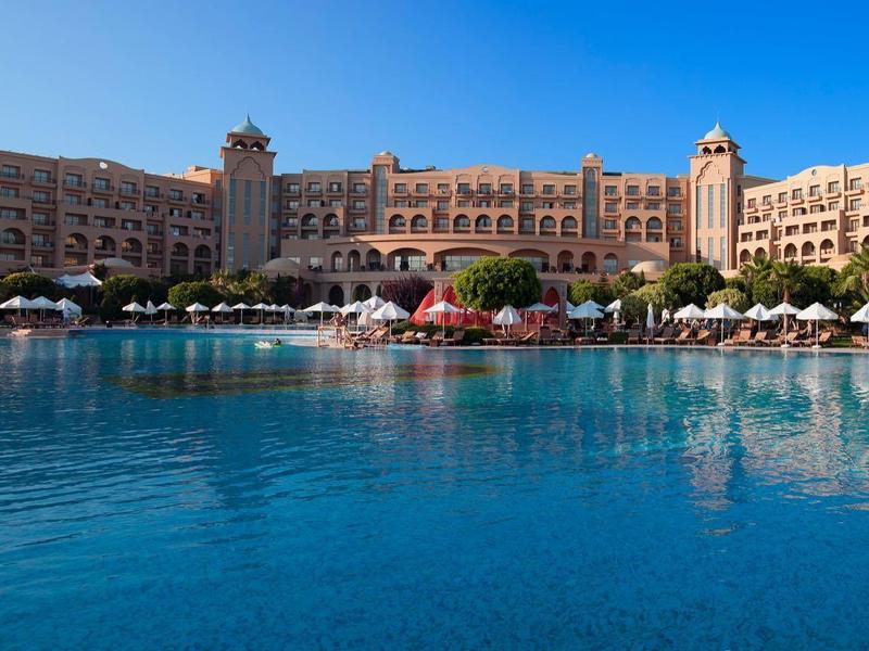 Luksusowy hotel z dużymi wieżami i niebieską laguną na pierwszym planie pod czystym niebem.