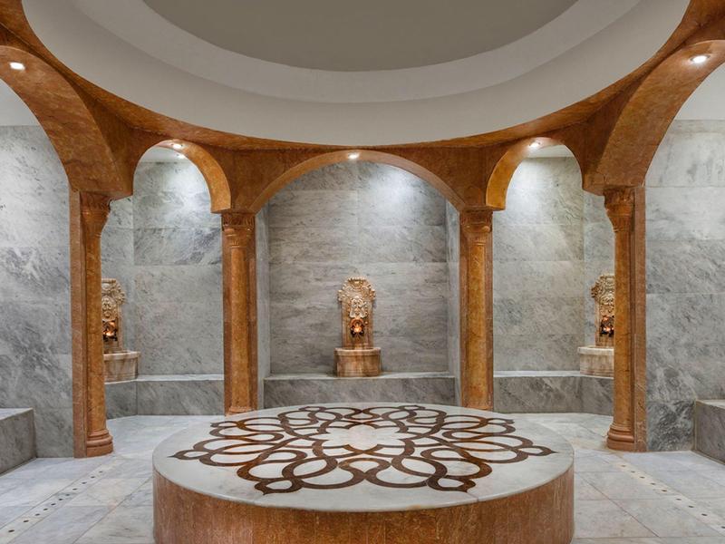 Luksusowa strefa spa z marmurowymi ławkami i ozdobnymi drewnianymi kolumnami.