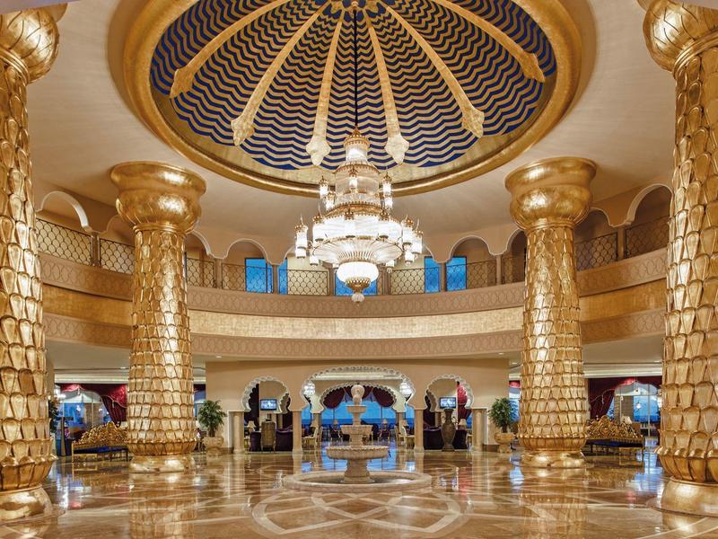 Luksusowe wnętrze hotelu z złotymi kolumnami, ozdobną kopułą i błyszczącą podłogą