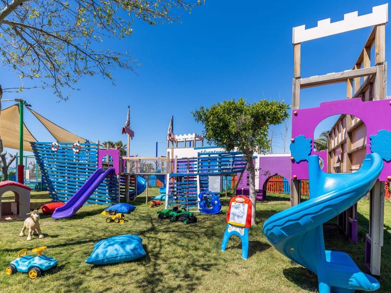Kolorowy plac zabaw dla dzieci z zjeżdżalniami i sprzętem do wspinaczki na trawie pod niebieskim niebem